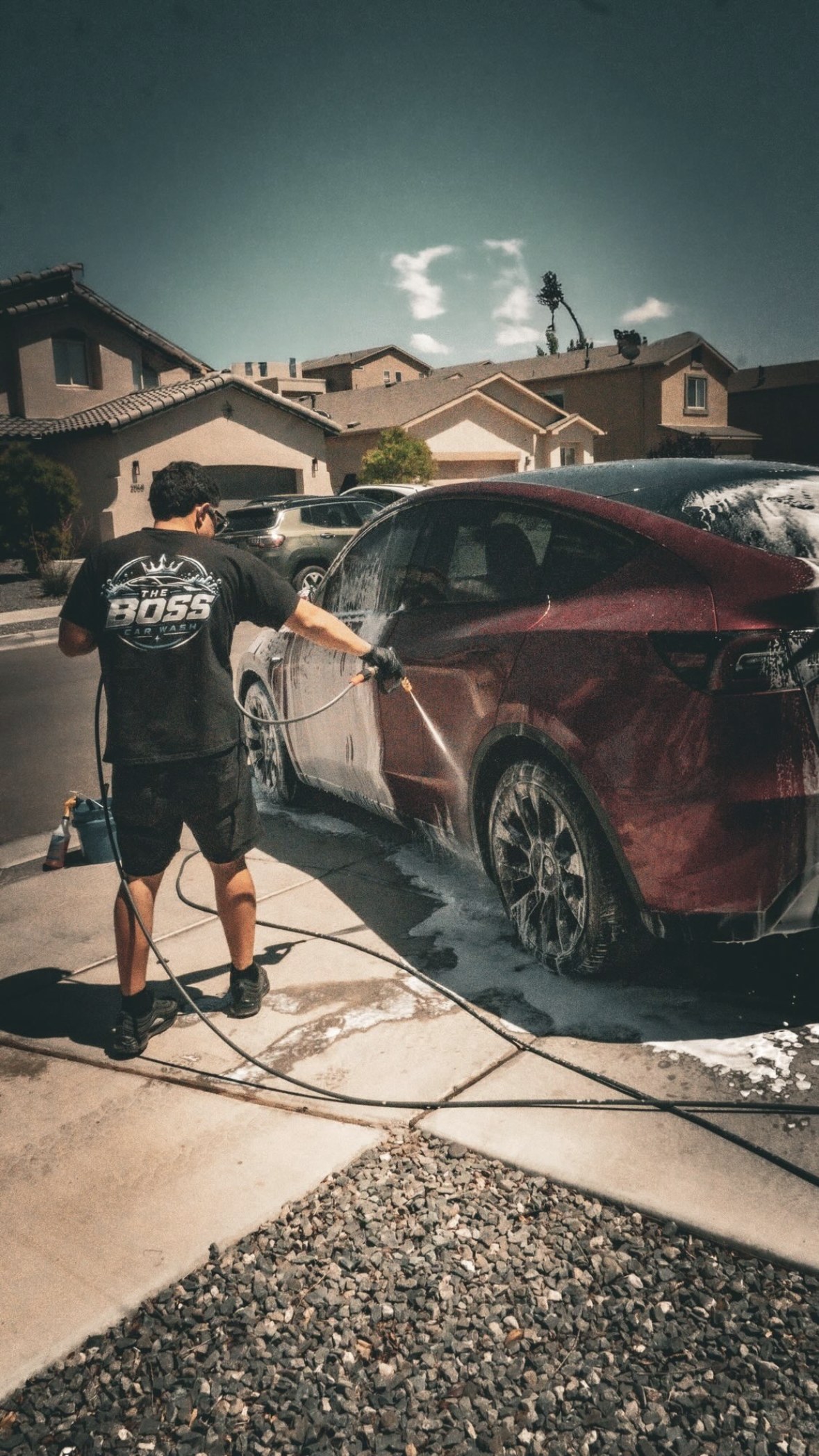 The Boss pressure washing a red Tesla